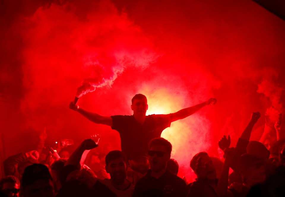 Arsenal fans with flares outside a stadium.