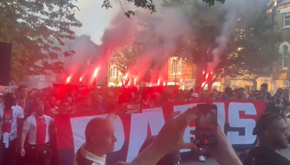 PSG fans in London with flares and a banner.