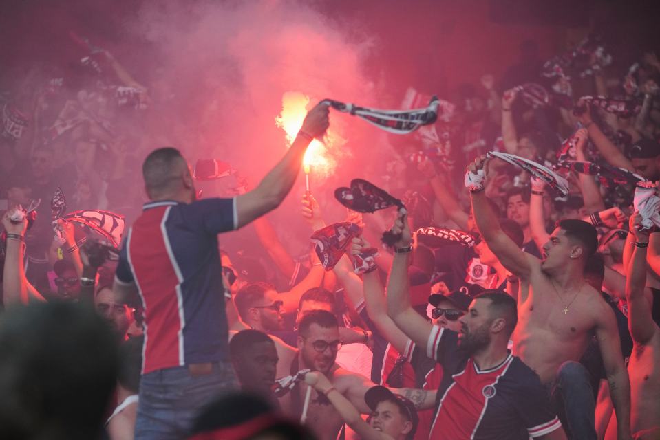 PSG fans celebrating with flares and scarves.