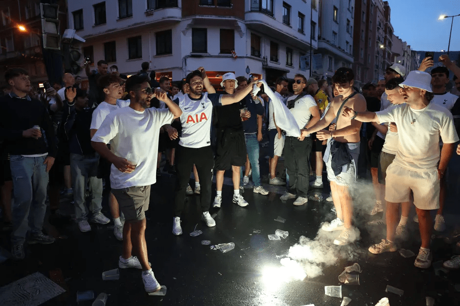 Crowd of soccer fans celebrating in the street with smoke bombs.