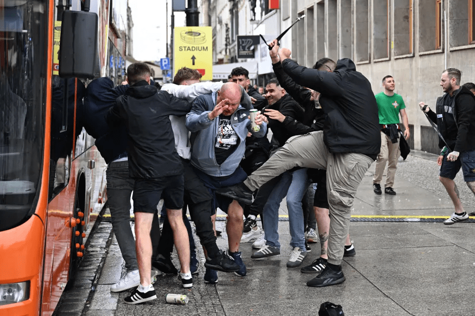 A group of people fighting near a bus.