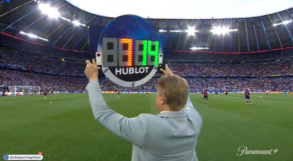 Person holding up a Hublot scoreboard at a soccer game.