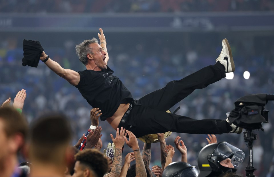 Paris Saint-Germain's head coach Luis Enrique being lifted in celebration by his players.