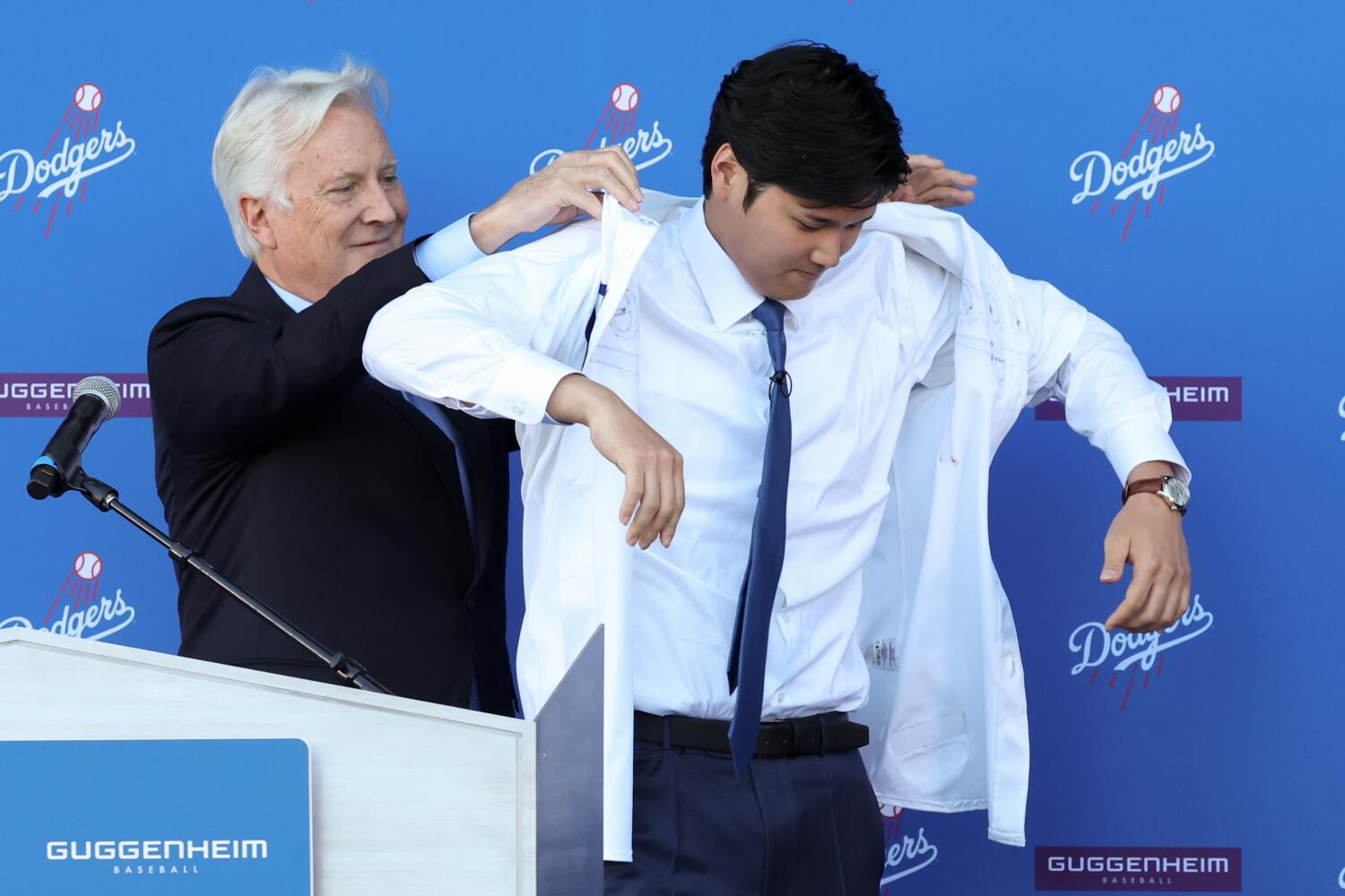 Dodgers owner Mark Walter helps Shohei Ohtani put on his new jersey during an introductory news conference.